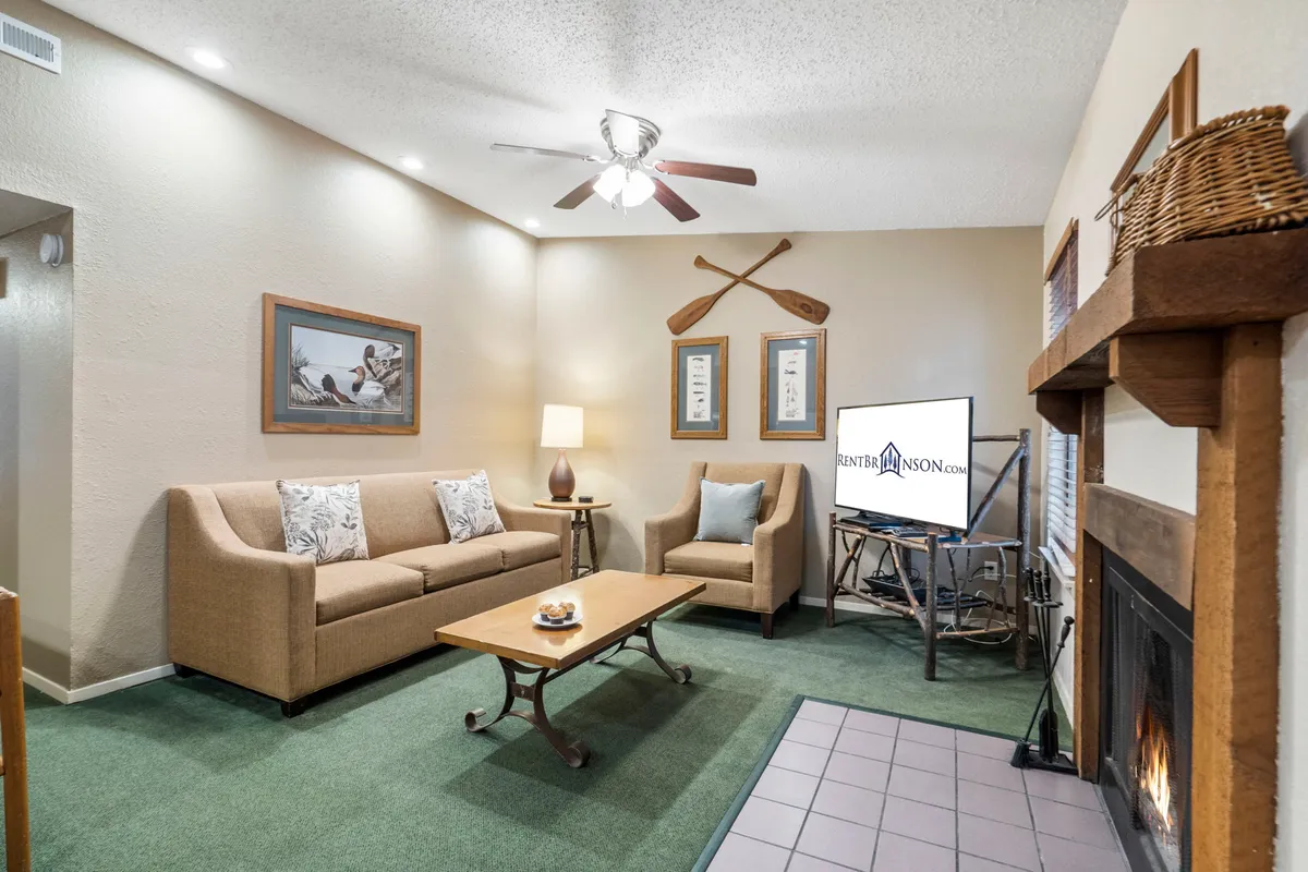 A cozy corner of the living room, spotlighting a plush sofa facing a coffee table, fireplace, and a smart TV mounted on the wall. The warm tones and soft lighting underline the room’s inviting atmosphere for movie nights or relaxed evenings by the fire.