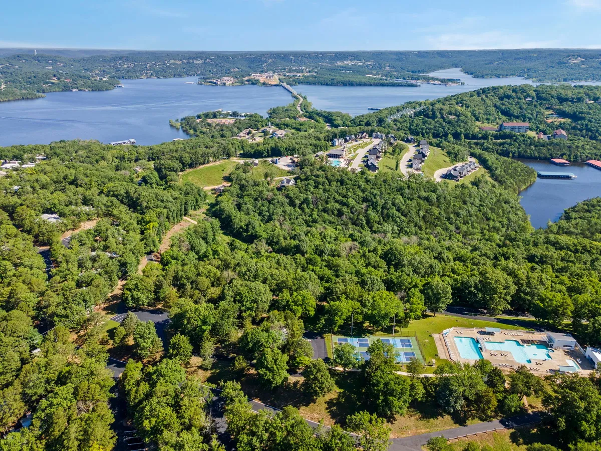 A panoramic community view that spotlights the expansive lake, lush greenery, residential amenities like the pool area, and nearby buildings. The image captures a lively, recreational atmosphere with ample opportunities for water sports, relaxation, and family fun.