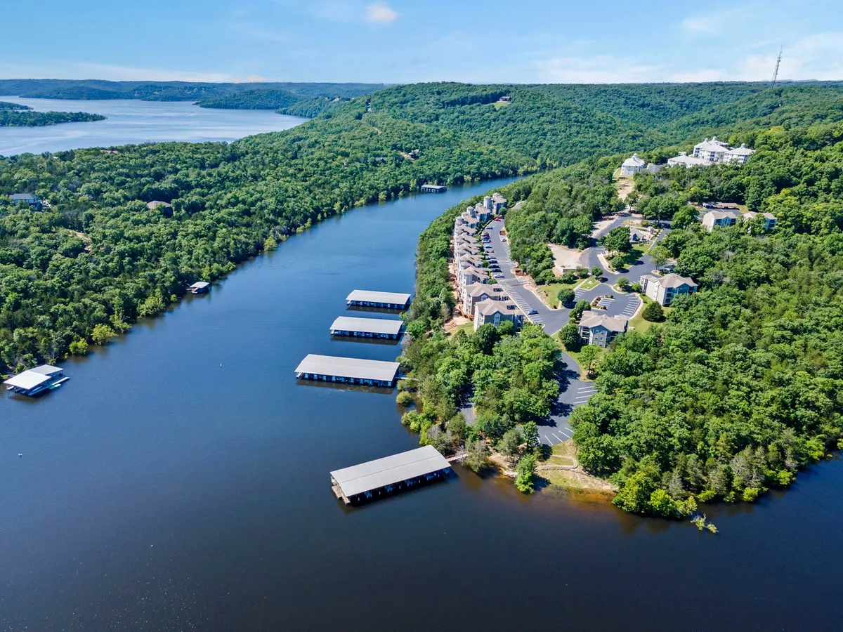A riverside landscape featuring wooded hills, a marina, and scattered residential buildings. The natural setting suggests plentiful areas for walks, exploration, and enjoying the outdoors with pets.